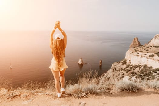 Woman travel sea. Happy tourist taking picture outdoors for memories. Woman traveler looks at the edge of the cliff on the sea bay of mountains, sharing travel adventure journey.