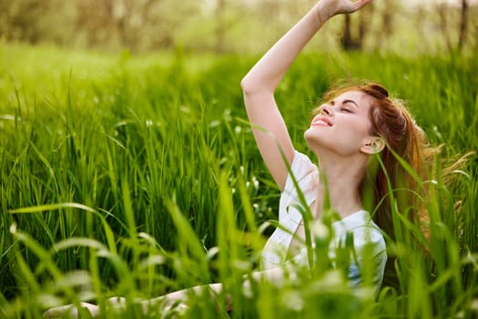 portrait of a beautiful woman sitting in tall grass and holding her long hair. High quality photo