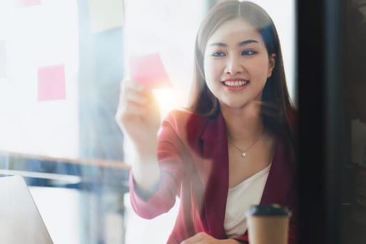 Smiling Asian Banker makes financial report and studies annual figures, analyzes profits. Accountant checks status of financial.