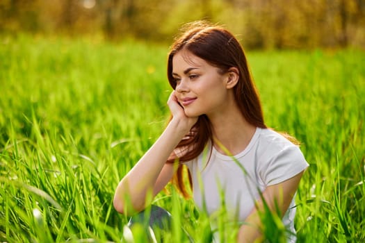 Portrait of young beautiful pensive dreamy woman lying on grass at summer green park . High quality photo