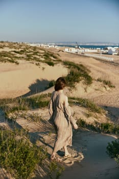 a woman walks on the sand away from the sea in windy weather enjoying the pleasant weather with her back to the camera. High quality photo