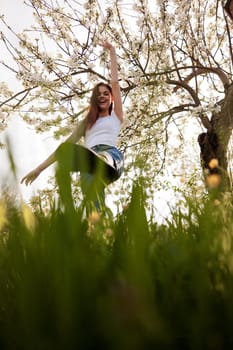 active woman posing raising her leg up against the background of a flowering tree in the park. High quality photo