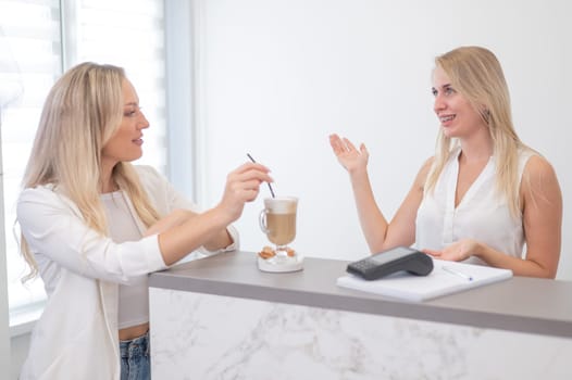 Receptionist in a beauty salon prepares coffee for a client