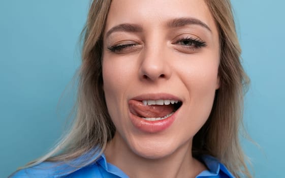 close-up of a blond coquette girl winking on a blue background.