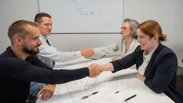 Business partners shake hands. Four business people are negotiating in the conference room