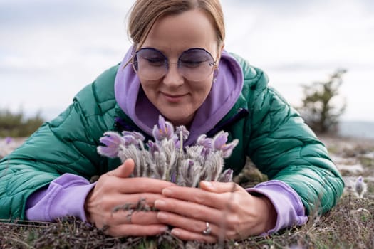 Dream grass woman spring flower. Woman lies on the ground and hugs flowers pasqueflower or Pulsatilla Grandis flowers.