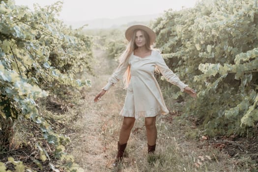 Woman at autumn winery. Portrait of happy woman holding glass of wine and enjoying in vineyard. Elegant young lady in hat toasting with wineglass smiling cheerfully enjoying her stay at vineyard