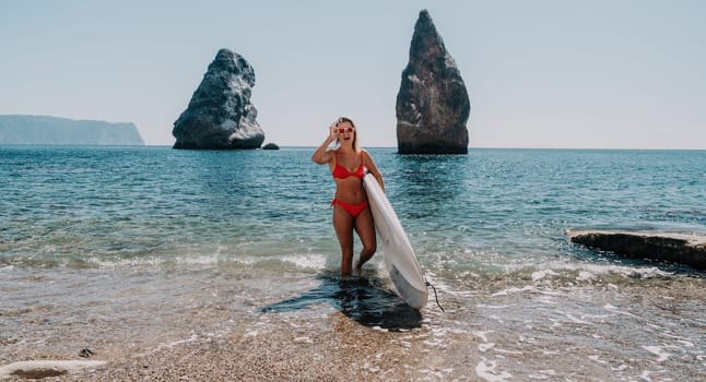 Close up shot of beautiful young caucasian woman with black hair and freckles looking at camera and smiling. Cute woman portrait in a pink bikini posing on a volcanic rock high above the sea