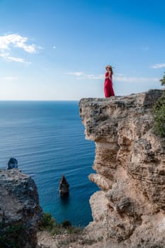 A woman in a red flying dress fluttering in the wind, against the backdrop of the sea