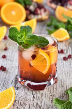 The cocktail is made from pomegranate and orange juice with tequila or gin, with the addition of tonic. Served in a glass with ice, orange slices with pomegranate and a sprig of mint. Cocktail recipe for any party.