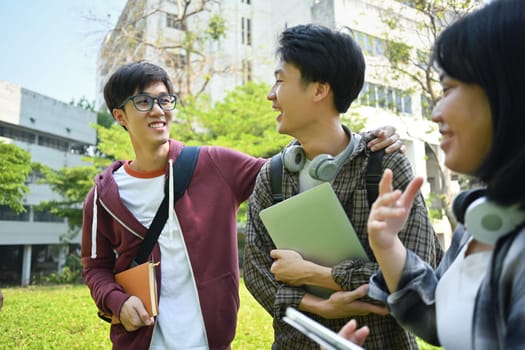 Group of cheerful college students talking to each other while going to lecture at the university. Youth lifestyle and friendship concept.