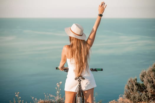 A woman cyclist on a mountain bike looking at the landscape sea. Adventure travel on bike