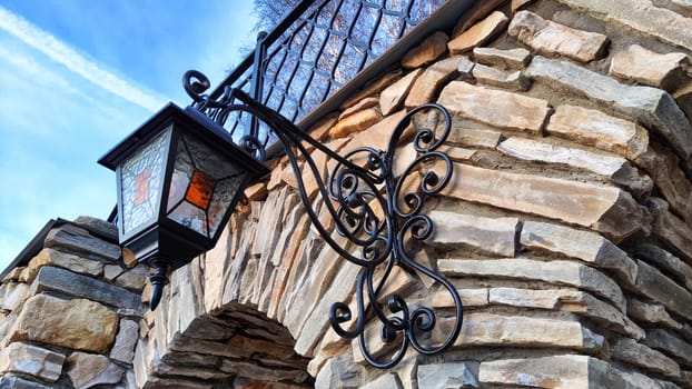 Part of the decoration of stone facade of building with vintage lantern on blue sky background