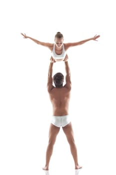 Image of two young gymnasts - man holds slim girl, isolated on white