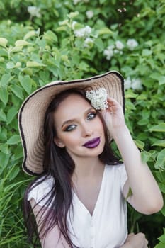 A fashionable girl with dark hair, a spring portrait in lilac tones in summer. Bright professional makeup