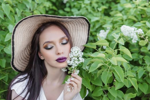 A fashionable girl with dark hair, a spring portrait in lilac tones in summer. Bright professional makeup