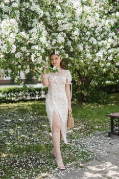 An attractive long-haired woman walks in the spring in the park of blooming apple trees. Spring portrait of a woman