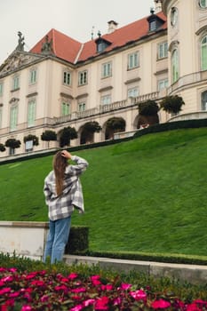 Female woman traveler sightseeing vacation holiday concept Beautiful violet flowers Castle Gardens on background adjacent to the Royal Castle in Warsaw from the side of the Vistula. City landmarks. Tourist attraction