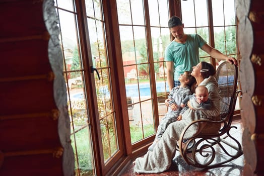 Happy mother and father have a rest indoors with their little son and daughter.