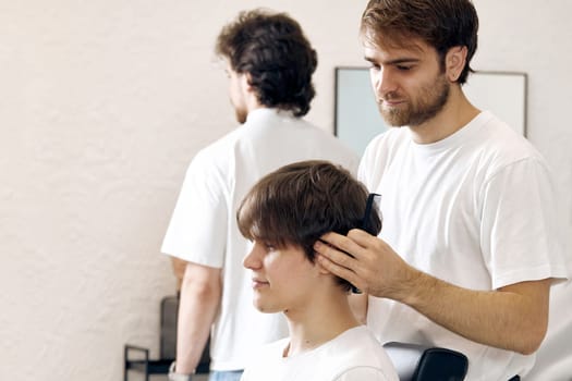 Barber combing caucasian man while sitting in chair before haircut at barbershop. client tells what haircut he wants