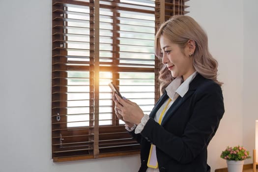 Smiling businesswoman using phone in office. business entrepreneur looking at her mobile phone and smiling.