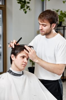 handsome young man visiting professional hairstylist in barber shop