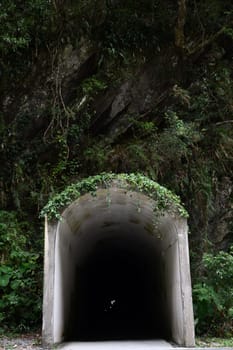 Vertical shot of an entry of a long and dark tunnel in the mountains at Tianxiang, Xiulin