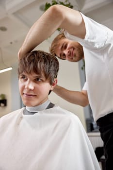 young caucasian man getting haircut by professional male hairstylist at barber shop.