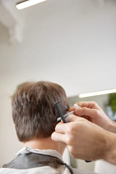 hairdresser does haircut for caucasian man in barber shop. close-up