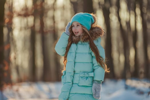 girl in turquoise clothes in a snowy forest