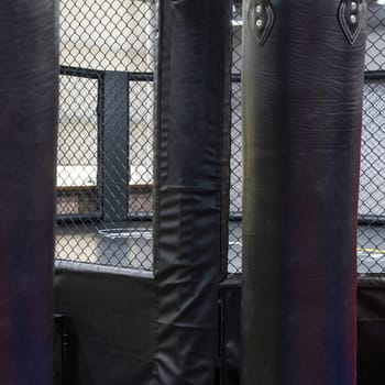 An octagonal kickboxing cage with boxing bags in the sports complex