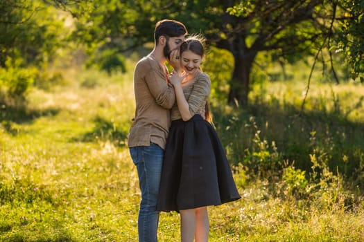 man tells in his ear the secret of his girlfriend walking in the park