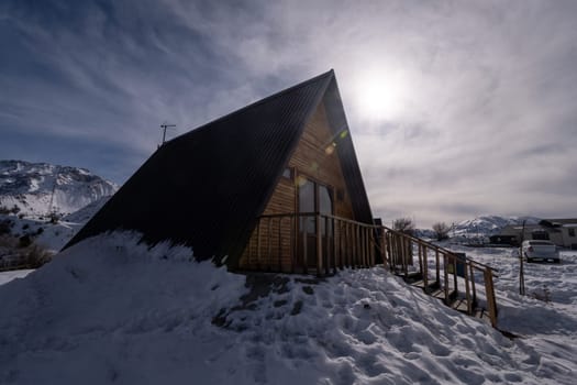 A wooden cottage surrounded by snow. A recreation area in the mountains