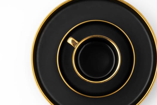 A set of black and golden ceramic plates and cup on a white background. Top view