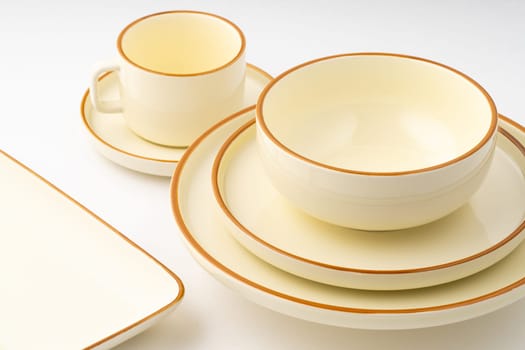 A set of white and brown ceramic plate and cup on a white background