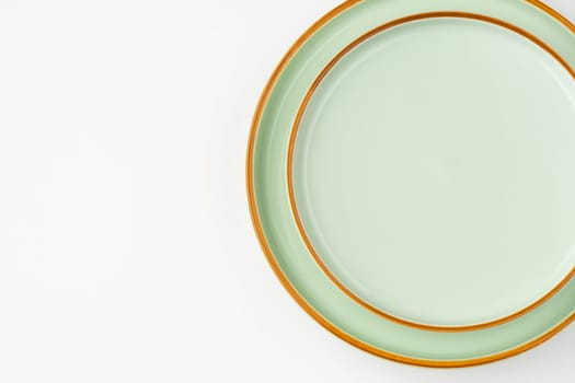 A set of pastel green ceramic tableware with orange outlines. Top view