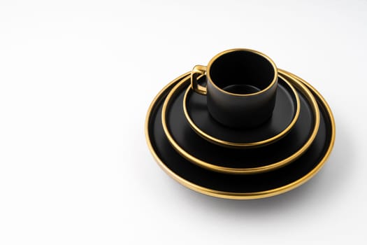 A set of black and golden ceramic plates and cup on a white background