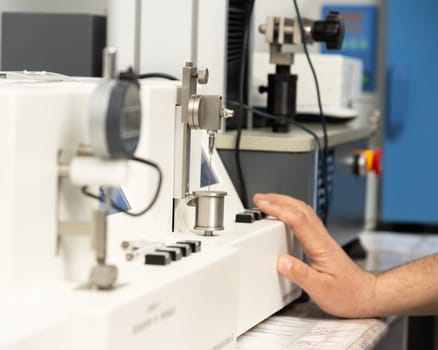 A closeup shot of a hand using a medical machine to test and manufacture pharmaceutical syringes