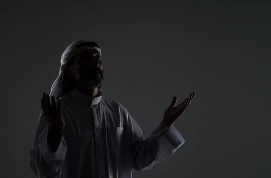 Muslim Arab man captures his spiritual devotion and faith as he prays, with hands raised to face in contemplation. Copy space for designers and publishers, black and white mid-length portrait . High quality photo