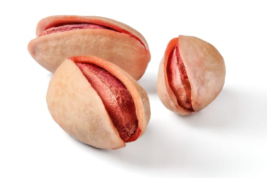 Three roasted, salted, red turkish pistachios isolated on white background.