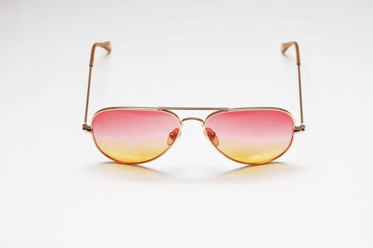 Beautiful sunglasses with a yellow-red gradient on a white wall background close-up. for promo or advertising banner.