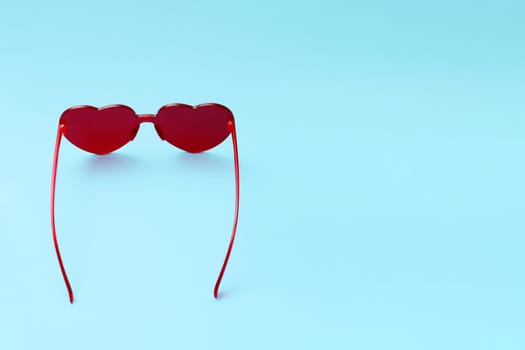 Beautiful sunglasses in the shape of a heart on a blue background.