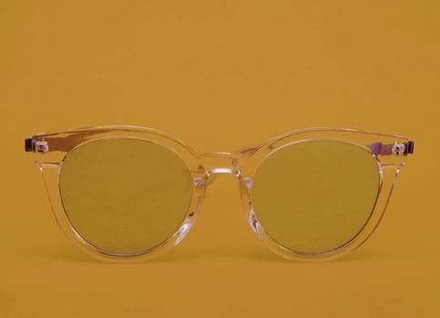 Light transparent plastic glasses on an orange background close-up front view.