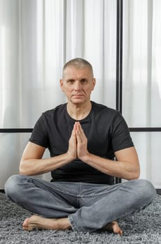 The concept of a healthy lifestyle. Portrait of a man who meditates in the lotus position on a yoga mat during a break at work.