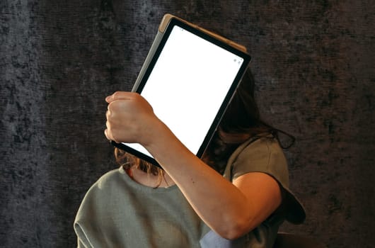 Portrait of a young woman who covers her face with a tablet. Mockup
