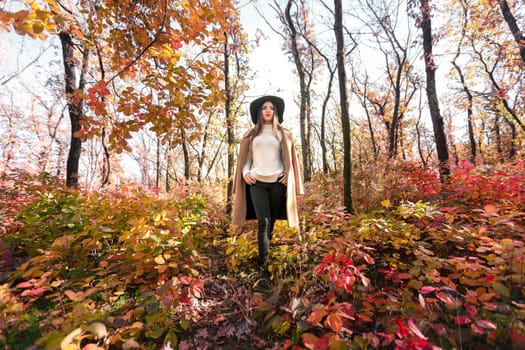 beautiful young woman in coat and black hat in park in the autumn