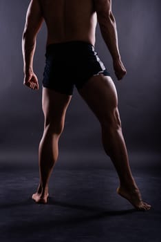 Muscular male legs close up studio shot on dark background