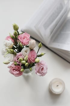 Details of still life in the home interior of living room. Flowers, book, candle. Moody. Cozy spring concept.