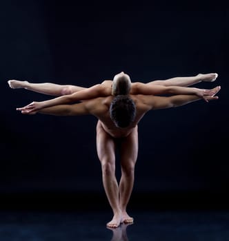 Image of two naked acrobats showing trick, on blue background