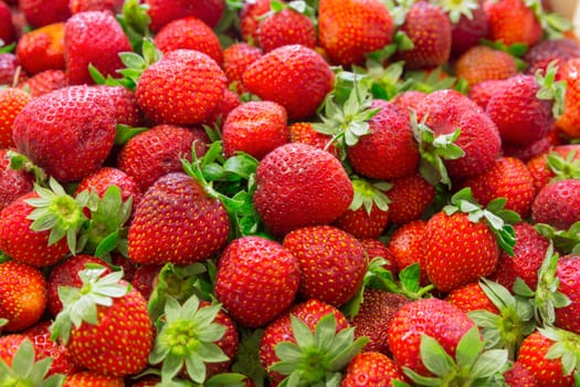 Background of beautiful and juicy strawberries with green leaves.
